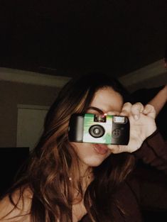 a woman holding up a camera to take a selfie in the dark with it's reflection