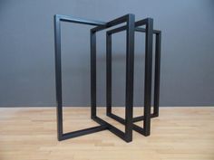 two black frames sitting on top of a hard wood floor in front of a gray wall