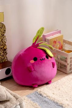 a pink stuffed animal sitting on top of a wooden floor next to a white basket