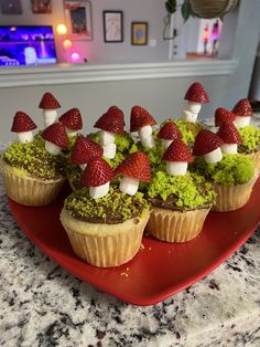 cupcakes decorated with strawberries and mushrooms on a red plate sitting on a counter