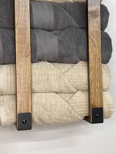 a stack of folded towels and blankets with wooden straps hanging on the wall in front of them