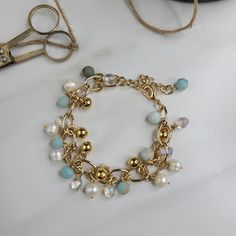 Our River handmade bracelet embodies the sun shining on water. It is handmade with amazonite beads, freshwater pearls, gold plated beads, and faceted crystal glass beads. Together these shine and sparkle, casting a little magic throughout your day. This bracelet was designed and made for you in the United States. A coordinating necklace and earring set is available. Features: - Gold Plated Cable Chain - Amazonite Beads - Freshwater Pearls - Faceted Crystal Glass Beads - Gold Plated Beads - Lobst Gold Beaded Bracelets With Pearl And Gemstone Beads, Gold Pearl Bracelets With Gemstone Beads, Handmade Gold Beaded Glass Bracelets, Gold Bohemian Pearl Bracelet With Gemstone Beads, Bohemian Gold Pearl Bracelet With Gemstone Beads, Whimsical Handmade Pearl Jewelry, Gold Beaded Bracelets With Amazonite Round Beads, Gold Amazonite Bracelet Jewelry, Amazonite Bracelet Jewelry In Gold