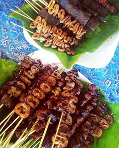 several skewers of food sitting on top of green leaves