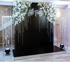 a black wall decorated with white flowers and chains hanging from it's sides in front of a staircase