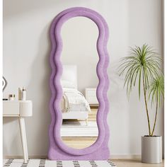 a large purple mirror sitting on top of a wooden floor next to a white table