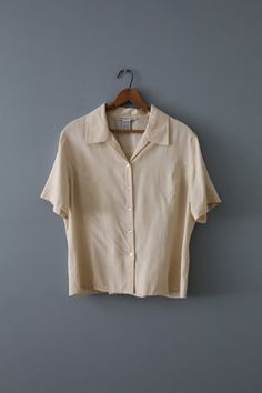 Vintage cropped silk top in beige color. Tie back closure. Button down front. 100% silk Made by Anna & Frank Fits like large: 16" shoulders  42" bust 22" length 9" sleeves Excellent condition! (Small stain, see last photos) Elegant Cream Cropped Tops, Elegant Cropped Cream Top, Cream Silk Top For Workwear, Elegant Beige Cropped Blouse, Fitted Silk Summer Shirt, Chic Cream Cropped Blouse, Fitted Silk Shirt For Summer, Chic Cropped Silk Blouse, Elegant Cropped Summer Shirt