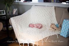 a baby wrapped in a blanket is laying on a couch next to a gift box