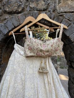 a dress hanging on a wooden hanger in front of a stone wall