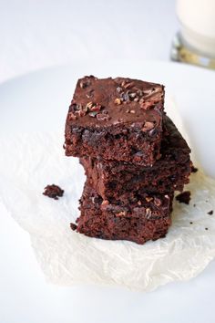 two brownies stacked on top of each other on a plate next to a glass of milk