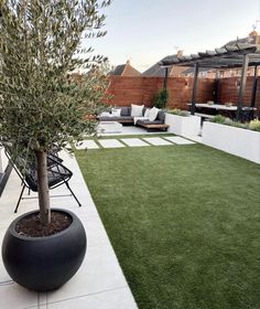 an outdoor living area with artificial grass and potted tree