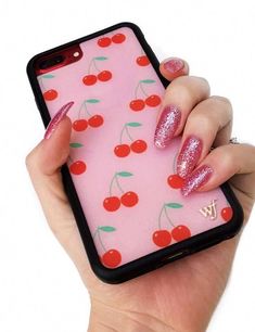 a woman's hand holding a pink phone case with red cherries on it