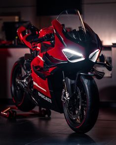 a red motorcycle parked in a kitchen next to a counter top with lights on it