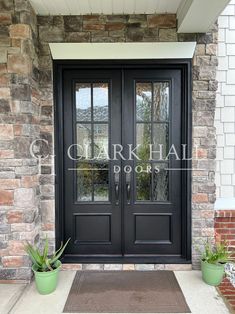 a black double door with two potted plants