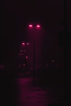 a street light in the dark with red lights on it's sides and no one around