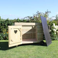 a small wooden dog house in the middle of a field with a heart shaped door