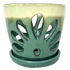 a green and white flower pot sitting on top of a table next to a candle holder