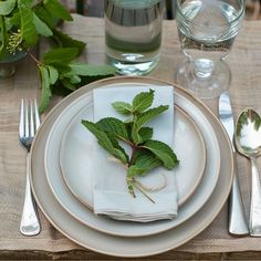 a place setting with silverware and green leaves