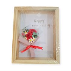 a flower in a wooden frame with the words happy anniversary written on it