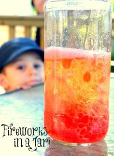 a glass filled with liquid sitting on top of a table next to a little boy