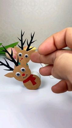 a hand holding a piece of paper with reindeers on it, and another person's finger