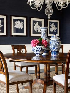 a dinning room table with chairs and vases on top of it in front of blue walls