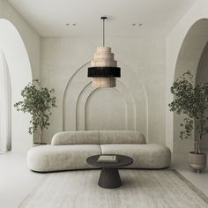 a modern living room with white walls and large round couches, potted plants on either side of the sofa