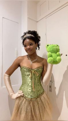 a woman wearing a green corset and holding a stuffed frog in her hand