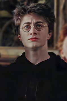 harry potter is staring at the camera in front of a woman with red hair and glasses