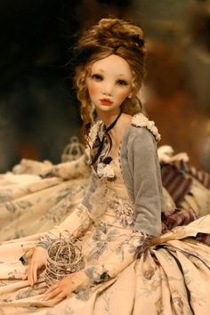 a doll sitting on top of a bed wearing a dress