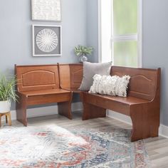 a wooden bench sitting on top of a rug next to a window