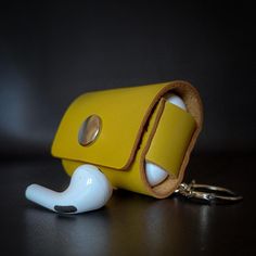 a yellow cell phone case with ear buds attached to it's sides and a keychain hanging off the side