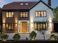 a large white house with lots of windows and lights on the side of it's front door