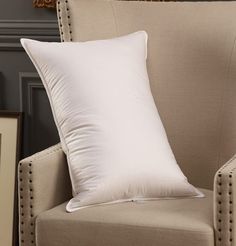 a white pillow sitting on top of a beige chair