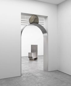 an arch with a rock on top of it in a white walled space between two walls