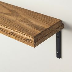 a close up of a wooden shelf with black metal brackets on it's sides