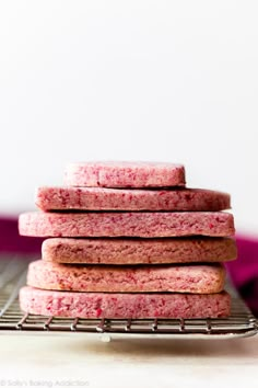 a stack of pink cookies sitting on top of a cooling rack