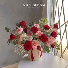 a vase filled with lots of red and pink flowers on top of a white table