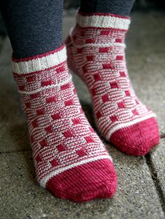 the legs of a person wearing red and white knitted socks with squares on them