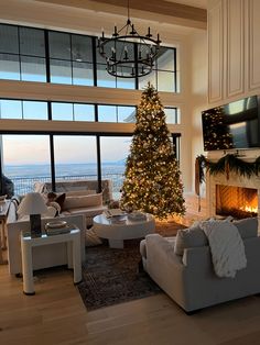 a living room filled with furniture and a christmas tree in front of a large window