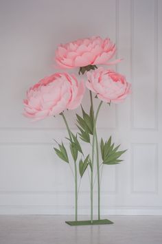 three large pink flowers are in a vase