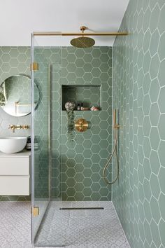 a bathroom with green hexagonal tiles on the walls, and a gold faucet