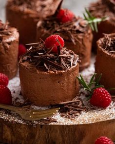 chocolate tart cakes with raspberries and powdered sugar on a wooden platter