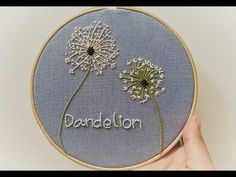 someone is holding up a embroidery project that says dandelion