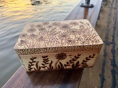 a wooden box sitting on top of a wooden bench next to a body of water