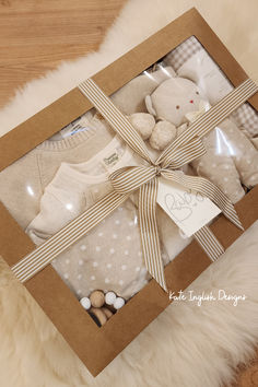 a baby's gift box with teddy bear, sweaters and other items in it