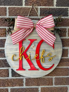 a wooden sign with the letter k is hanging on a brick wall