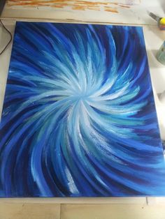 a painting is being worked on with blue and white swirls in the middle of it