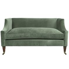 a green velvet couch with wooden legs