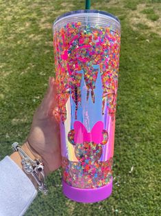 a person holding up a purple tumbler with colorful sprinkles on it