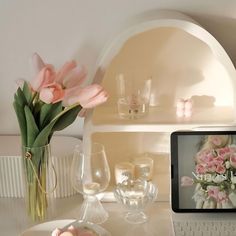 a laptop computer sitting on top of a desk next to a vase filled with flowers